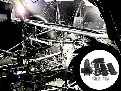 A black automotive sound deadening kit shown in a circular inset overlay, featuring a foam panel, adhesive strips, mounting hardware, and a speaker cover, set against a background of a stripped-out race car frame with a bright work light on.