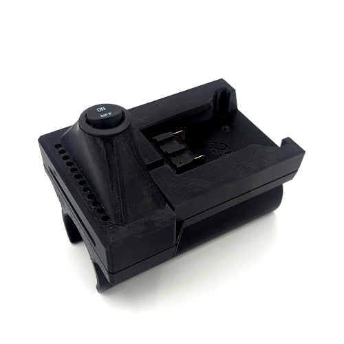 A black plastic camera battery charger or battery holder with a power switch, shown on a white background.